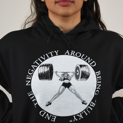 Close up of a Black hoodie sweater shirt with a white graphic design of a women powerlifter that says End The Negativity Around Being Bulky Graphic