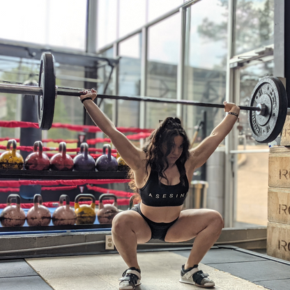 Powerlifter in the middle of a lift wearing the Asesina graphic sports bra. 